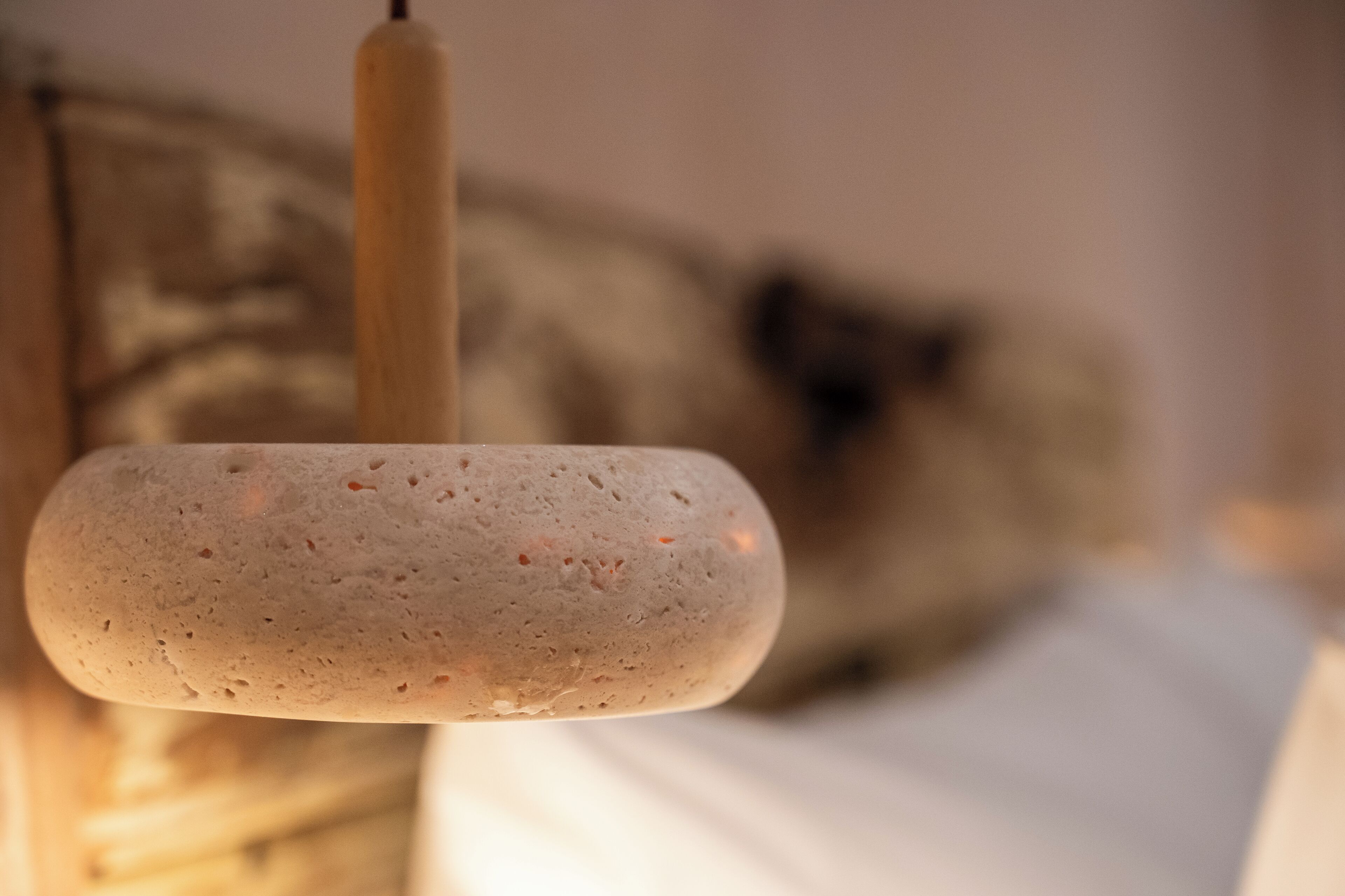 A close-up of a textured, oval-shaped object, possibly a decorative item, with a blurred background featuring a wooden structure and a white surface.