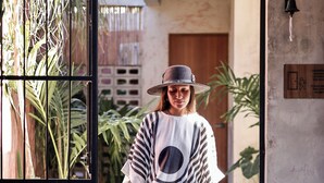 A person exiting through a black metal gate into a building with a concrete floor and potted plants. - Casa Coyote Holbox (Isla Holbox)
