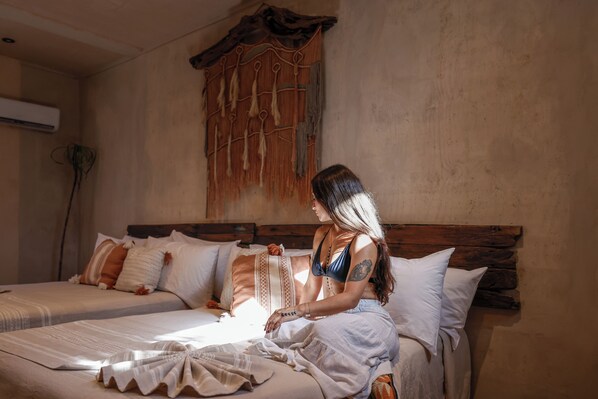 A room with two beds, a wooden headboard, and a wall-mounted air conditioner. - Casa Coyote Holbox (Isla Holbox)