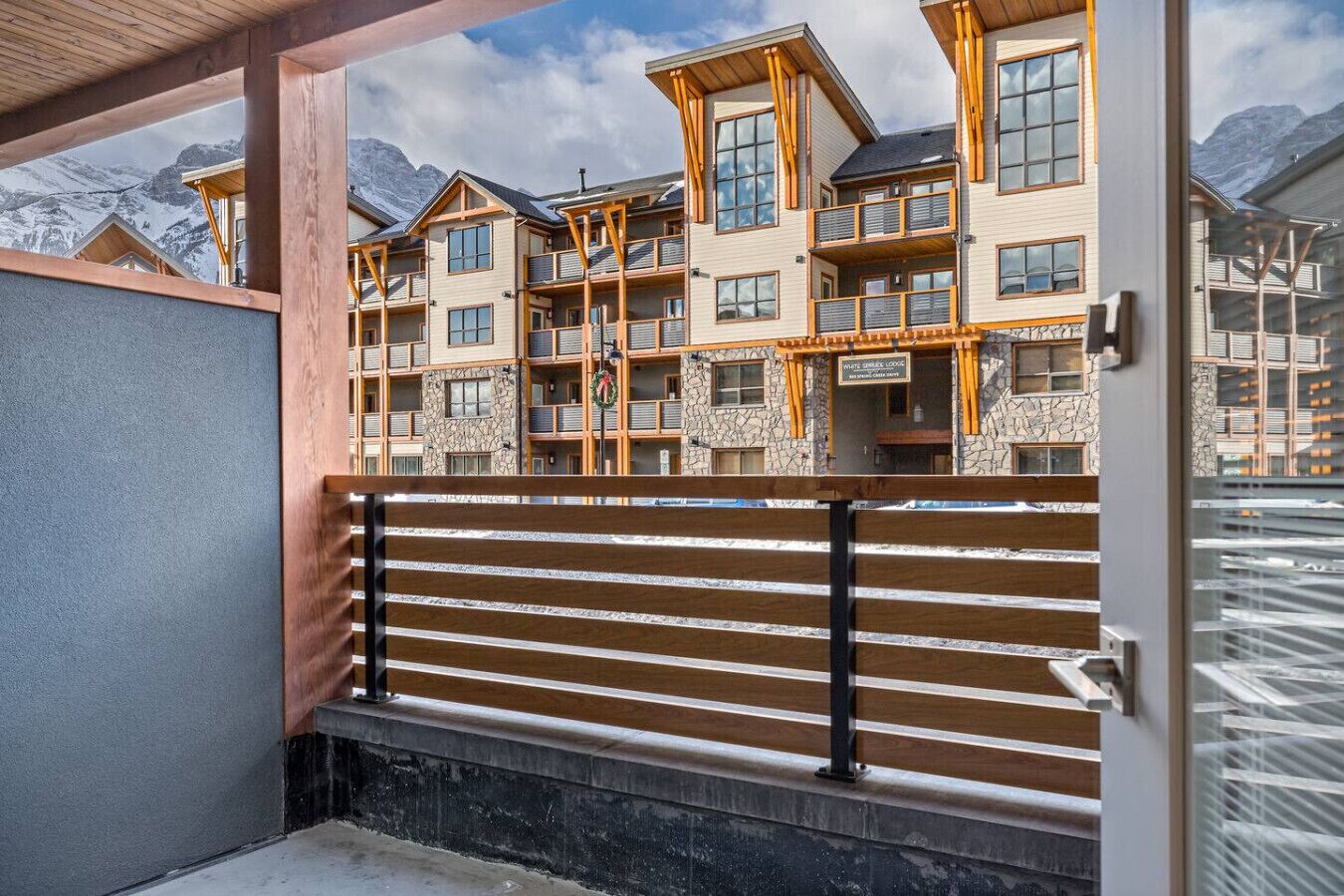 Un immeuble à plusieurs étages doté de balcons, d’une façade en pierre et offrant une vue sur les montagnes.