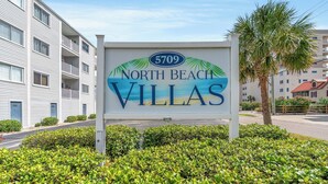 Schild für North Beach Villas mit Strandmotiv, das eine Lage direkt am Strand anzeigt.
