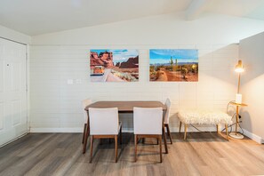 A dining area with a wooden table, four chairs, a bench, and two wall-mounted pictures. - 2KingBd  2Bath  Gym  Pool Free Parking (Scottsdale)