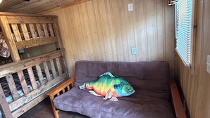 A wooden cabin interior with a couch, a wooden bench, and a window with blinds. - Cozy Northwoods property (Crivitz)