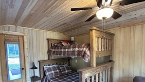 A bunk bed room with a ceiling fan, a wooden door, and a small table. - Cozy Northwoods property (Crivitz)