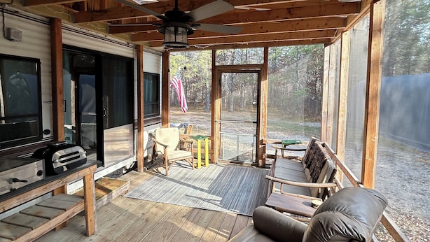 A covered outdoor living area with wooden beams, a ceiling fan, a grill, and a seating area with a sofa and chairs. - Cozy Northwoods property (Crivitz)