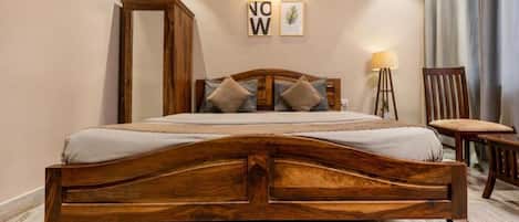 A wooden bed with a headboard, a bedside table, and a chair. There are two framed pictures on the wall.