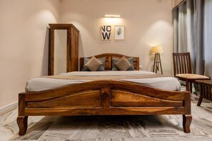 Un lit en bois avec une tête de lit, une table de chevet et une chaise. Deux tableaux encadrés sont accrochés au mur.