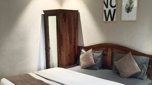 A bedroom with a wooden bed frame, a large bedspread, and a striped rug. - J Startup House (Jaipur)