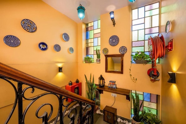 A staircase with ornate black railings, a red fire extinguisher, and decorative plates on the walls. - J Startup House (Jaipur)