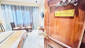 Une chambre d’hôtel avec un lit, un bureau, une chaise et une porte en bois avec une pancarte.