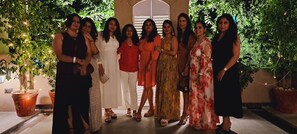 A group of people standing in an outdoor area with potted plants and string lights. - J Startup House (Jaipur)