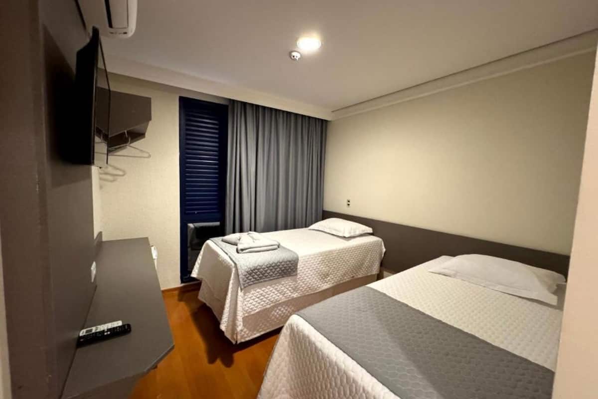 Une chambre d’hôtel avec deux lits, un téléviseur à écran plat et une fenêtre avec des rideaux.