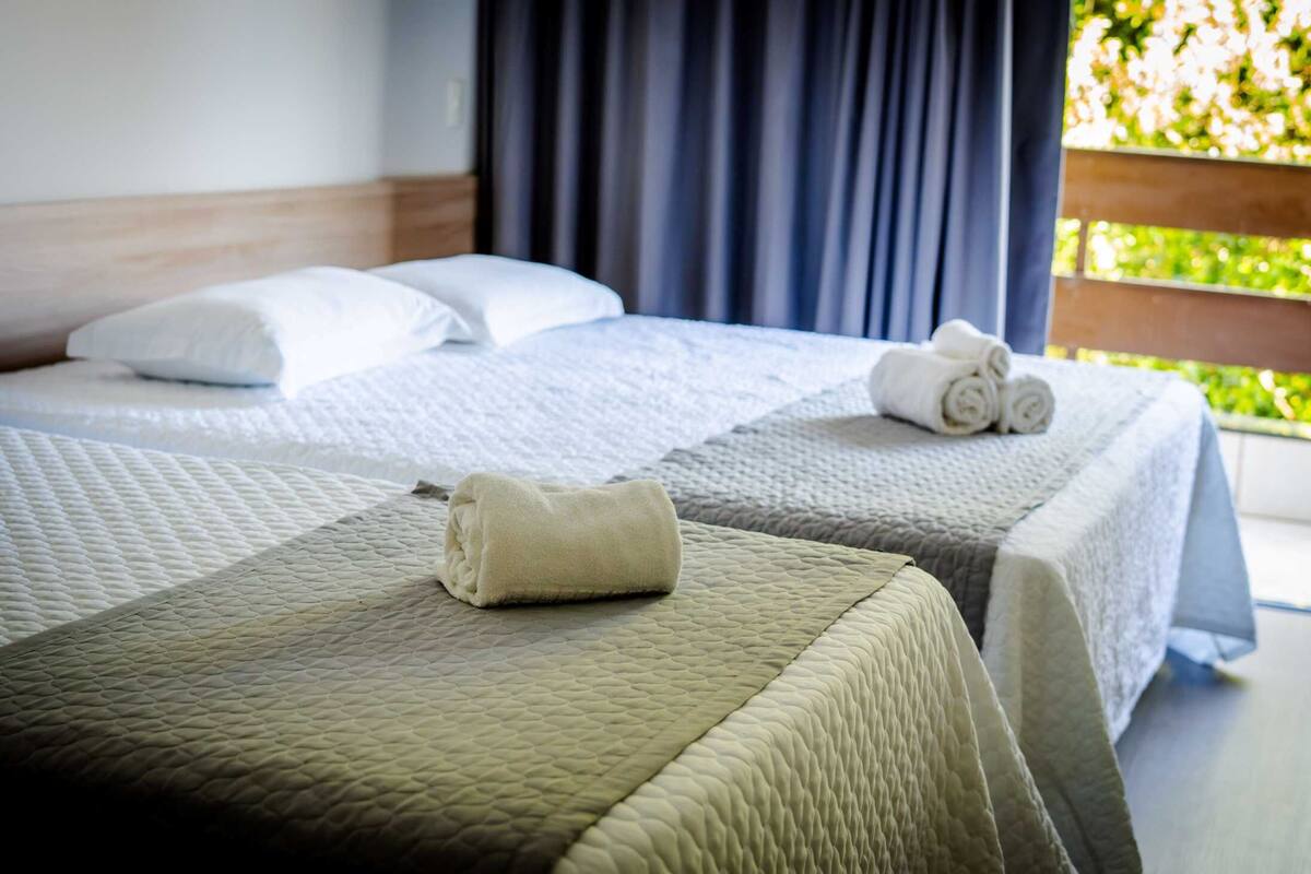 Une chambre d’hôtel avec deux lits, chacun étant agrémenté d’une courtepointe matelassée et de coussins.