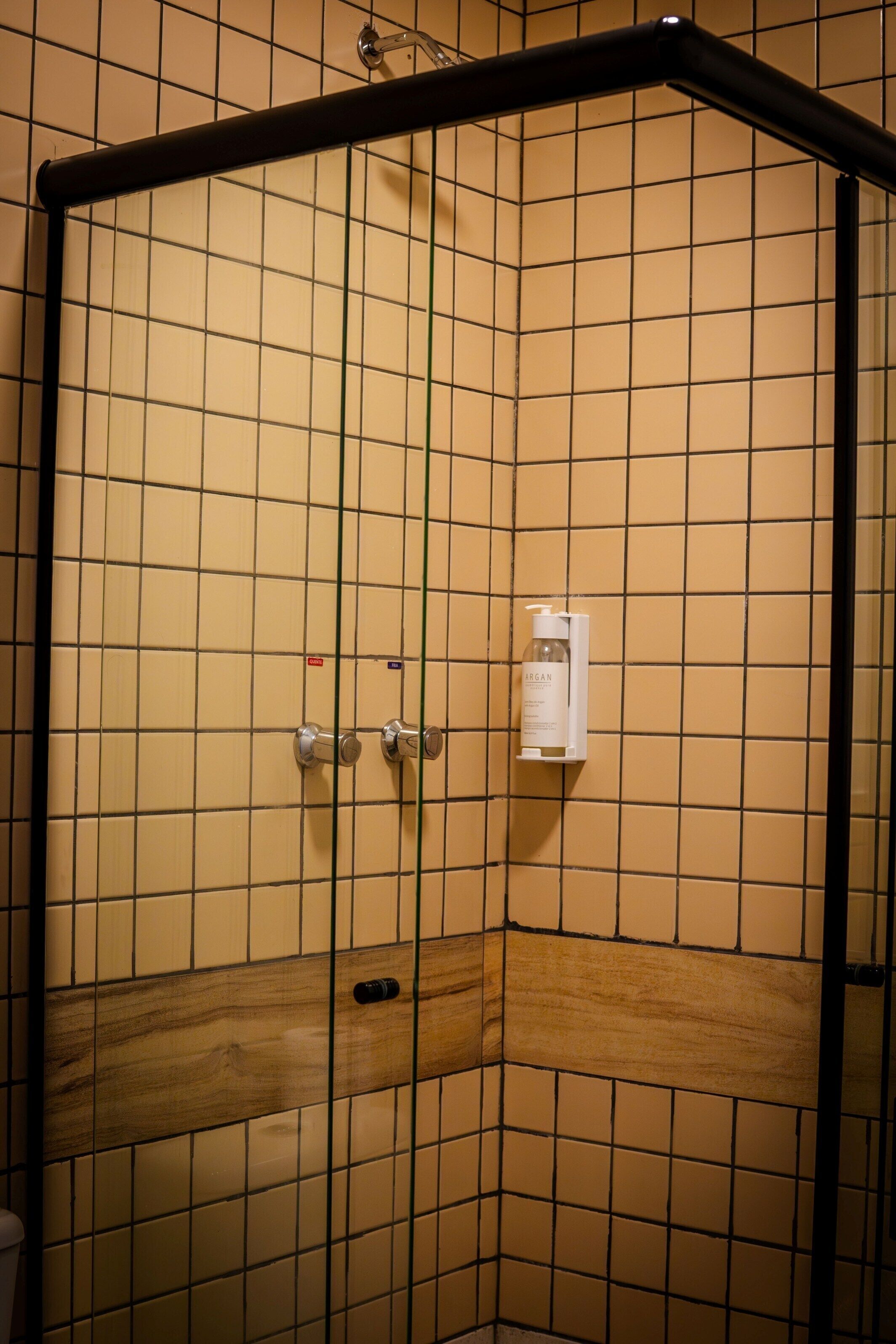 Eine Eckdusche mit gefliesten Wänden und einem Holzelement.