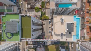 Une vue aérienne d’une ville avec ses immeubles de grande hauteur, un terrain de sport verdoyant et une piscine.