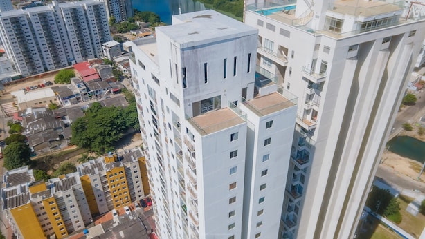 Un immeuble de grande hauteur doté de nombreux balcons et d’un espace piscine sur le toit.