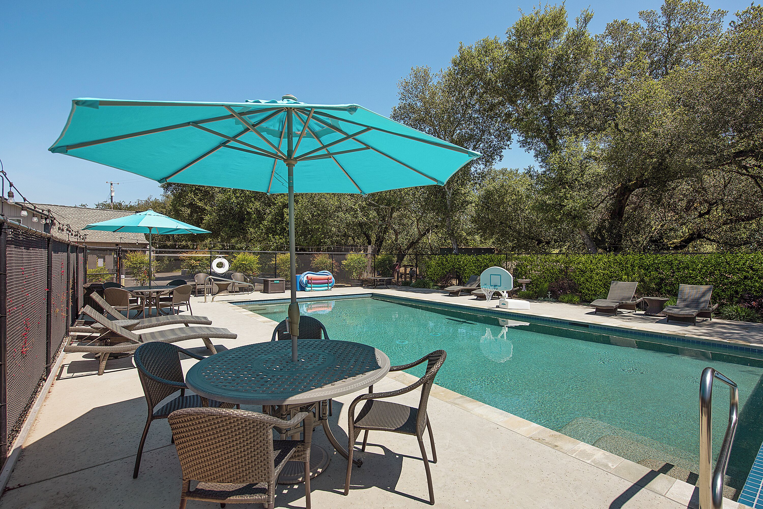 A pool area with lounge chairs, a table, and umbrellas.