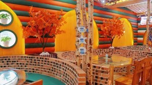 Un restaurante con diseño de pared de ladrillo, mesas redondas y plantas en macetas.