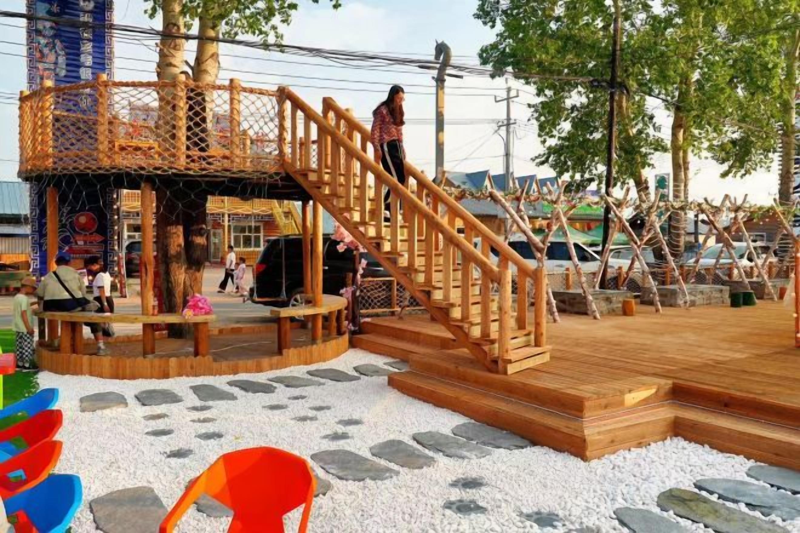 A wooden outdoor area with a circular seating arrangement and a staircase leading to a raised platform.
