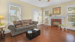 Un salon avec un canapé, une table basse, une cheminée et un ventilateur de plafond.