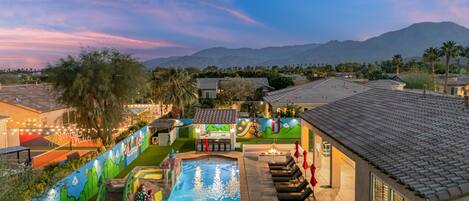 A pool area with a mural, a dining setup, and a view of mountains.