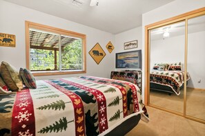 A bedroom with a large bed, a dresser, a television, and a mirror. - Sugarbear Cabin (Sugarloaf)