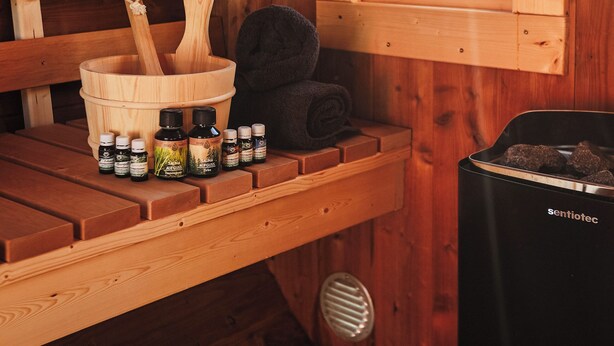 Een houten cabinemaker met een houten bank, een houten emmer met een houten lepel, en een zwarte verwarming met de aanduiding 'sentiotec'.