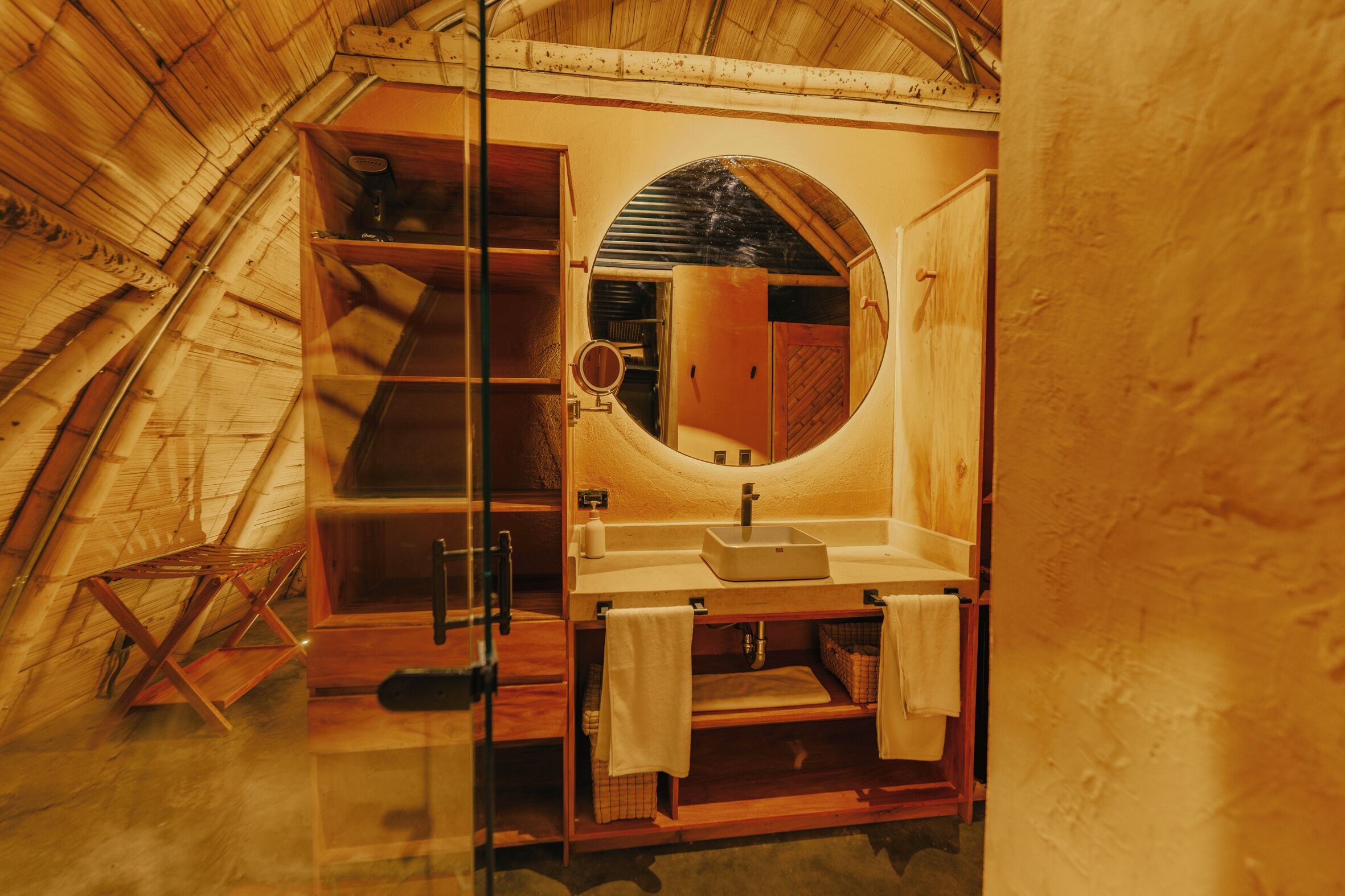 Een compacte badkamer met houten details, een ingebouwd wastafelmeubel, spiegel en opbergplanken.