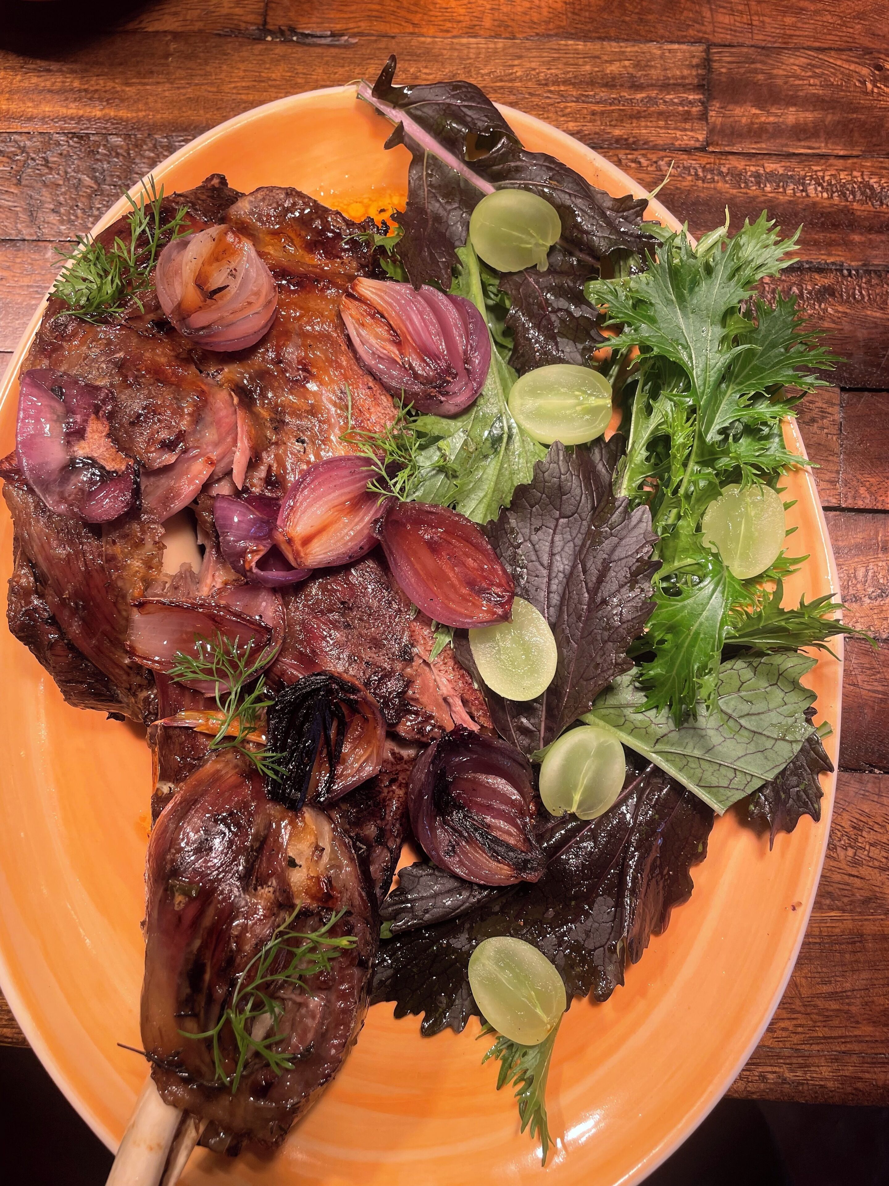 Un plato de comida con carne, cebollas y vegetales verdes.