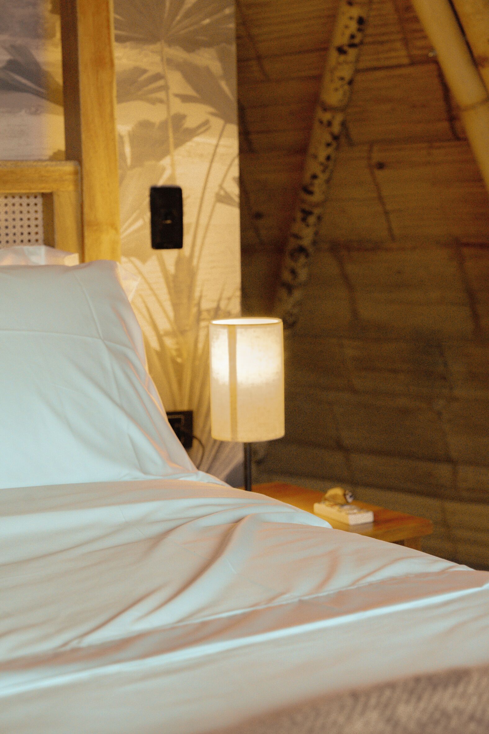 Un dormitorio con una cama, una mesita de noche, una lámpara y una pared con una escalera de madera.