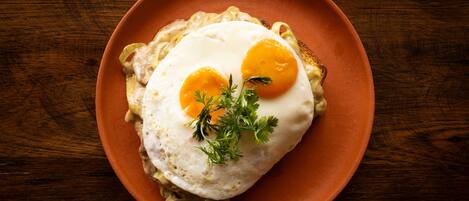A plate with two sunny-side-up eggs on toast, garnished with parsley, on a brown plate.