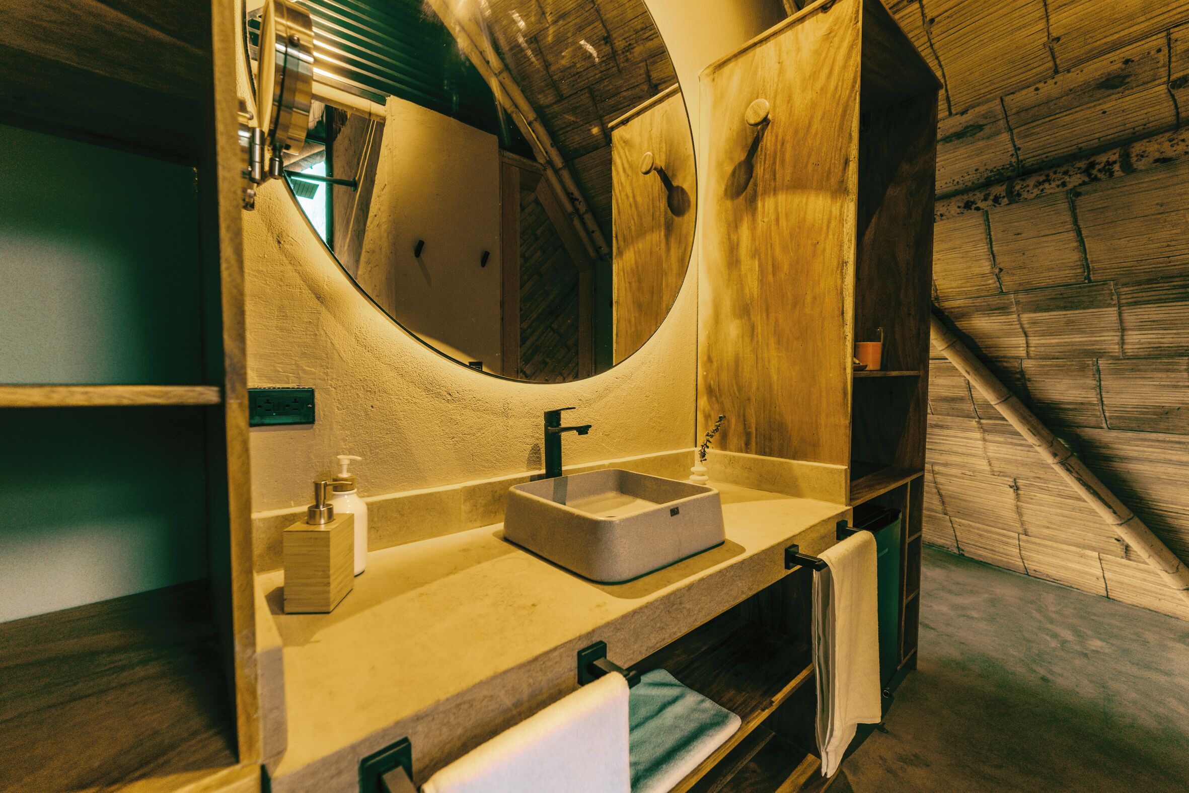Une salle de bain avec un meuble-lavabo en bois, un lavabo rectangulaire, un miroir et un porte-serviettes.