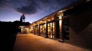 A building with large glass windows and a brick facade, featuring a hexagonal tile floor and a pathway leading to the entrance. - Hotel Casa Selvaggio (Ráquira)