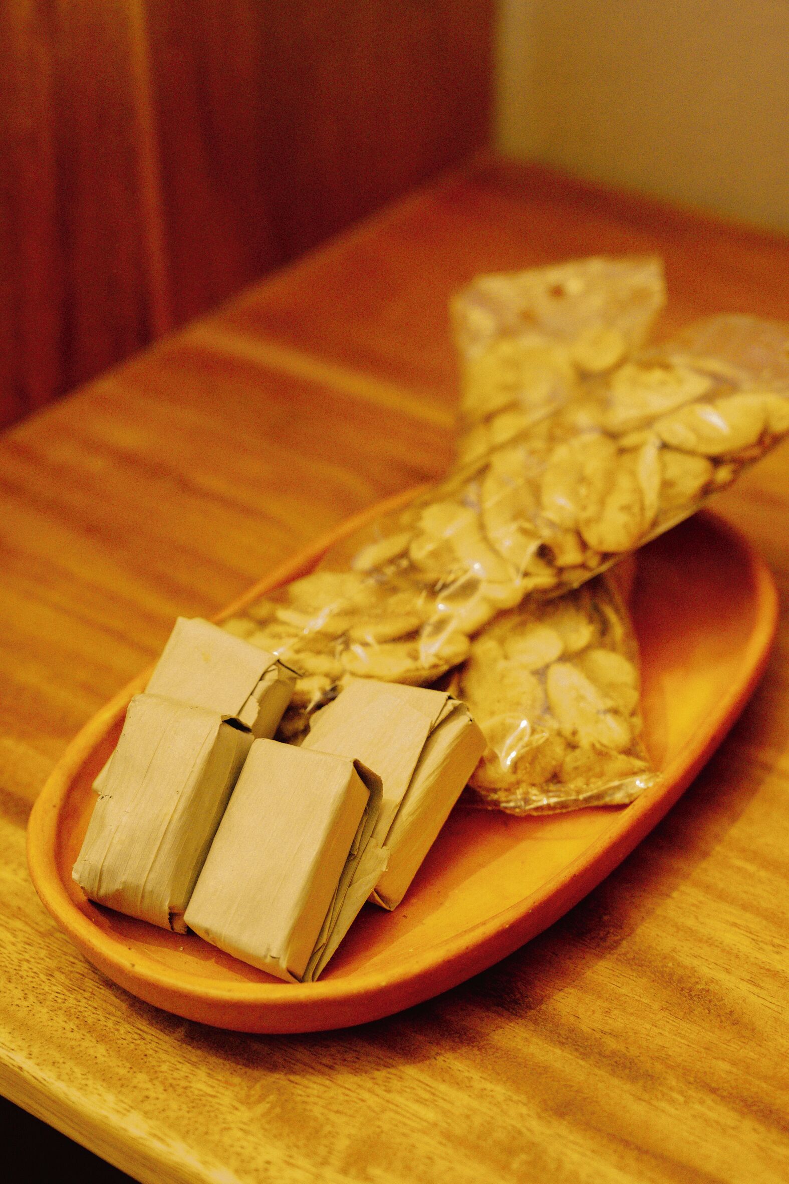 A wooden table with a plate containing packaged food items.