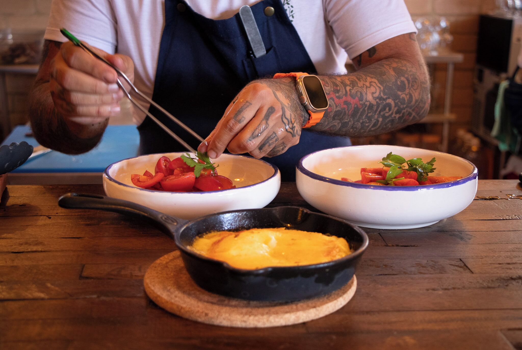 A person cooking with a pan on a wooden table.