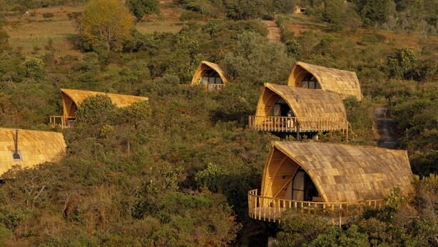 A series of wooden dome-shaped cabins nestled among trees on a hillside. - Hotel Casa Selvaggio (Ráquira)