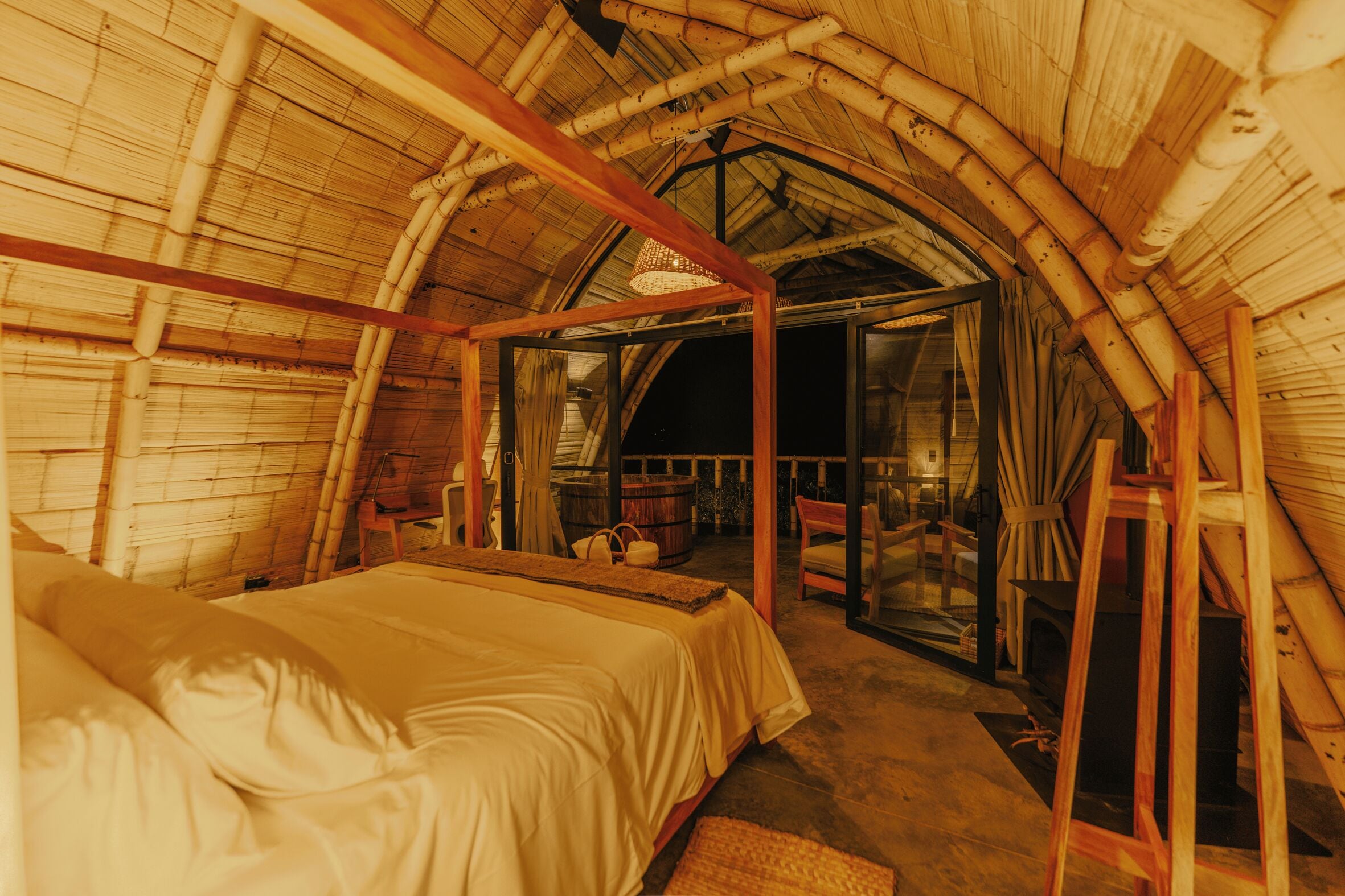 Une pièce avec un lit, un plafond en bois et une porte en verre donnant sur un autre espace.