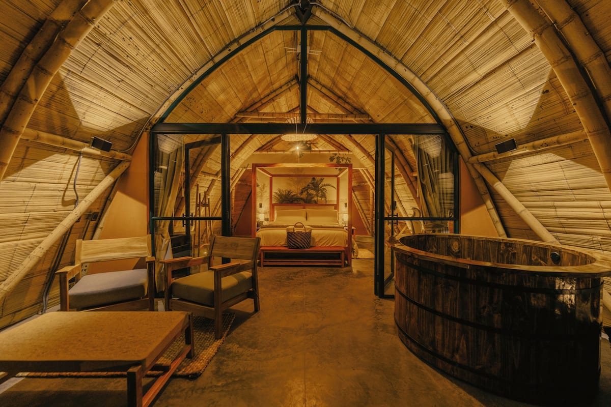 An attic room with a bed, seating area, and a hot tub.