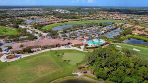 Vista aérea de un complejo turístico de golf con múltiples cuerpos de agua, un edificio central con piscina y abundante vegetación circundante.