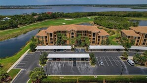 Un hotel de varios pisos con un patio central, estacionamiento y un campo de golf al fondo.