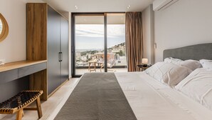 A modern hotel room with a large bed, a desk, and a view of the city. - Ionian Sol Apartment | Blue Horizon Stay by PikHost (Sarandë)