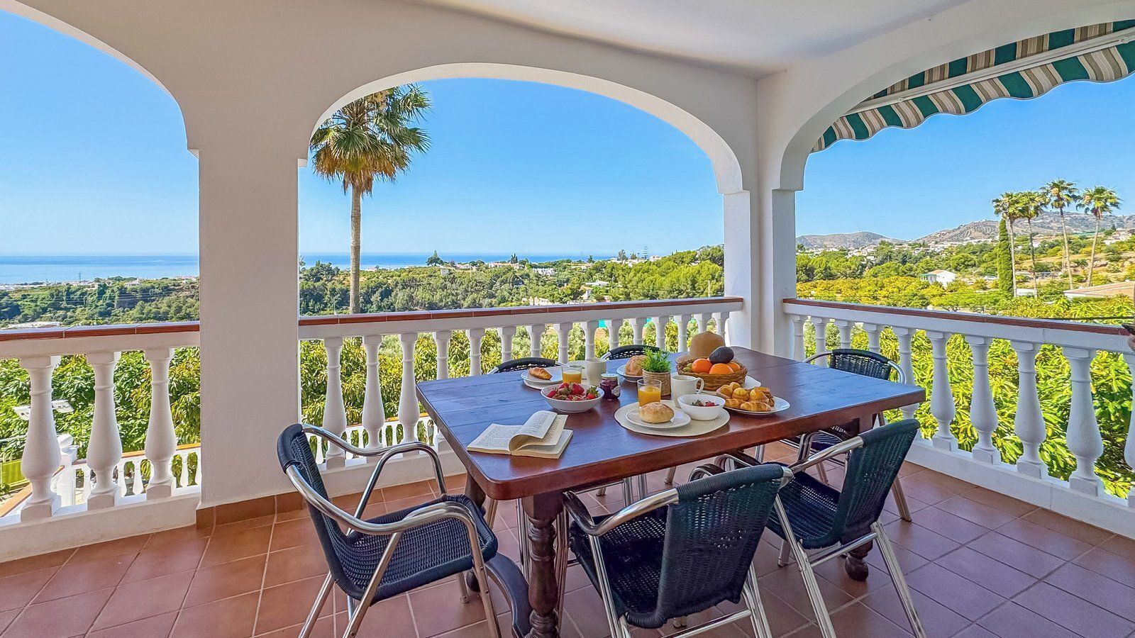 Un balcon avec une table préparée pour le petit-déjeuner, offrant une vue sur un paysage magnifique.