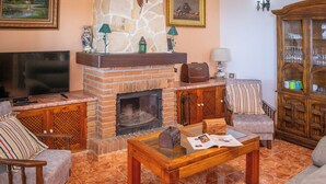 A living room with a fireplace, a television, and a wooden cabinet with glass doors.