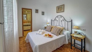 A neatly made bed with towels, a bedside table with a lamp, and a tray of breakfast items.