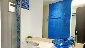 A bathroom with a blue tiled shower, a white toilet, a blue bowl sink, and a mirror. - 2 Bedroom Oceanfront Apartment with Restaurant (Cartagena de Indias)