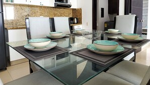 A modern kitchen with white cabinets, a microwave, and a dining area with a glass table and chairs. - 2 Bedroom Oceanfront Apartment with Restaurant (Cartagena de Indias)