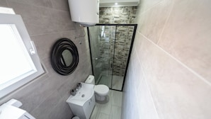 Un baño con inodoro, lavamanos y cabina de ducha de vidrio.