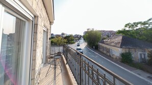 Un balcón con vista a una calle, un edificio con un letrero y un coche estacionado.