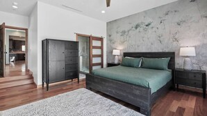A bedroom with a large bed, a wardrobe, a nightstand, and a bathroom with a glass shower. - Cloud-Break Ridge | Pool, Spa - Epic Mountain Views (Malibu)