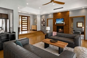 Una sala de estar moderna con chimenea, sofás de cuero, una mesa de centro de madera y una televisión.